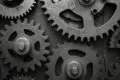 schwarze Zahnräder, die miteinander verbunden sind und zusammenarbeiten.
