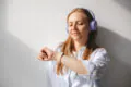 Blonde young woman wear shirt and listening to music with blue headphones