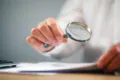 person reading documents with magnifying glass